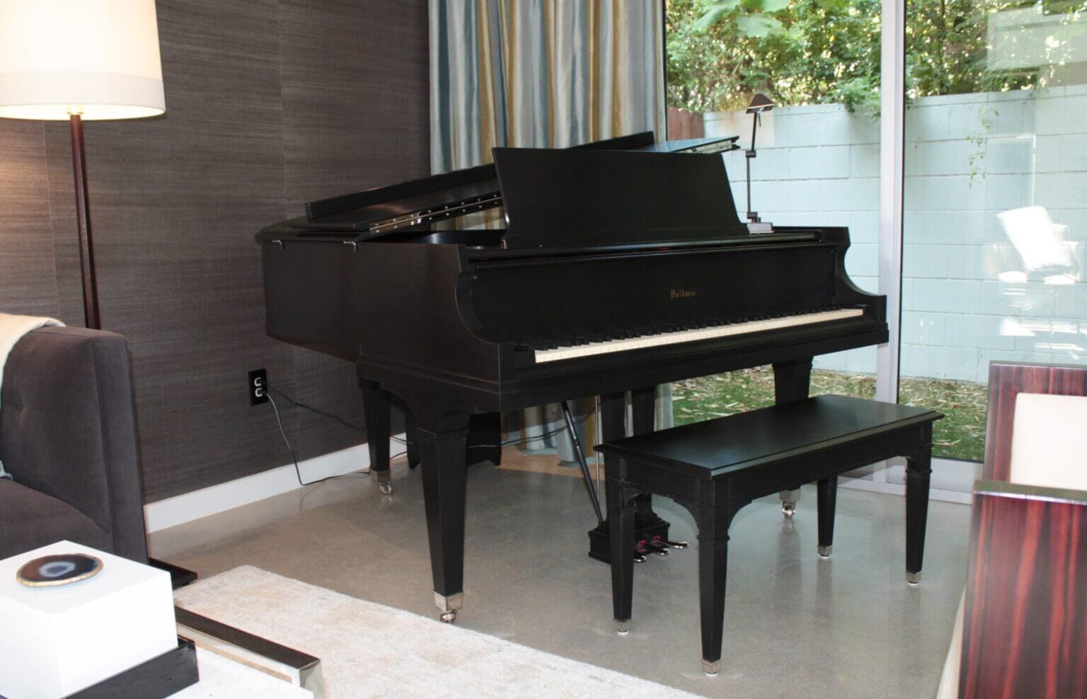 A black piano sitting in front of a window.