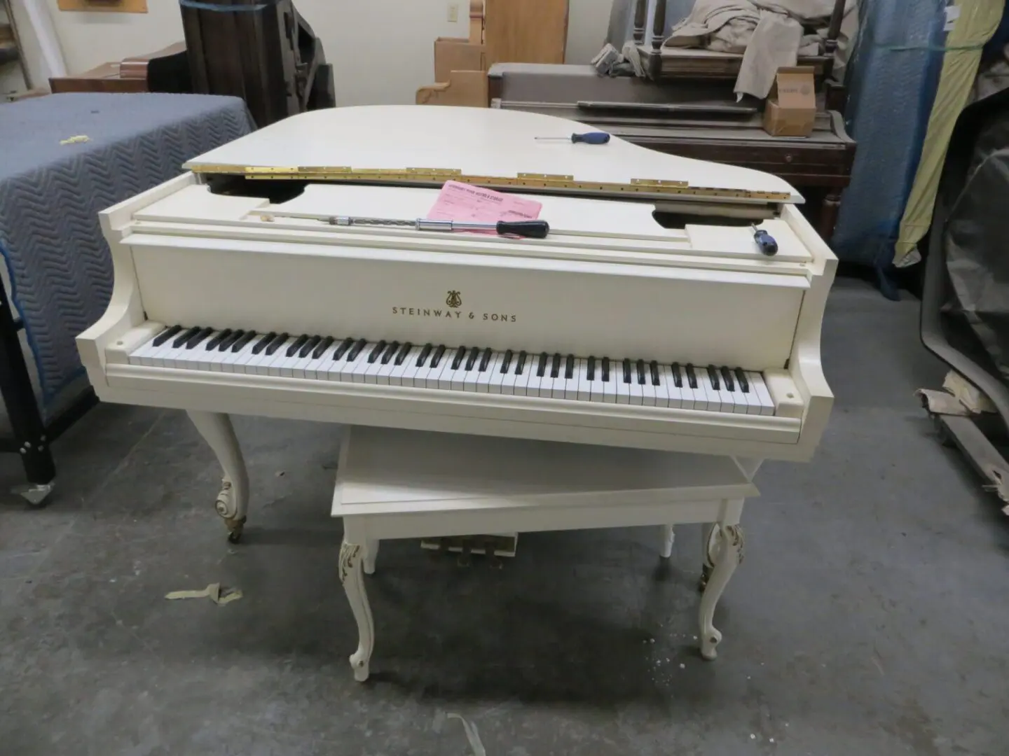 A white piano sitting on top of a wooden bench.